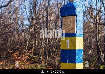 Ukrainisch blau und gelb Nummer eins Grenzsäule mit Wappen. Im Hintergrund der blaue Himmel und Bäume, Sträucher und Gras Stockfoto