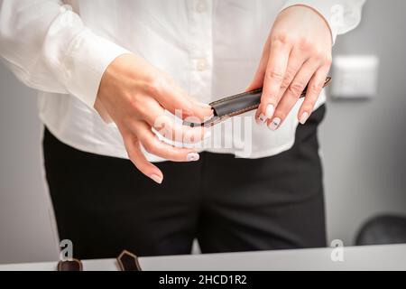 Gepflegte Hände und Werkzeuge für eine Maniküre. Hände des Manikuristen nehmen das Instrument für eine Maniküre aus dem Lederetui in einem Nagelstudio ab Stockfoto