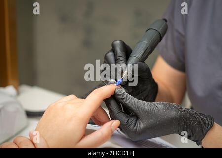 Manikurist entfernt Nagellack nutzt die elektrische Maschine der Nagelfeile während der Maniküre in einem Nagelstudio Stockfoto