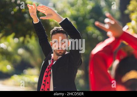 Mann, der die Arme hebt, während er Flamenco mit einer Frau im Flamenco-Kleid tanzt Stockfoto