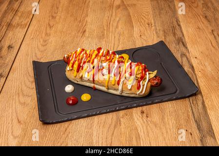 Der Hot Dog ist eine Kombination aus gekochter oder gebratener Wiener Wurst, die auf einem langen Brötchen serviert wird, das oft von einem Belag wie Ketchup, Mustar begleitet wird Stockfoto