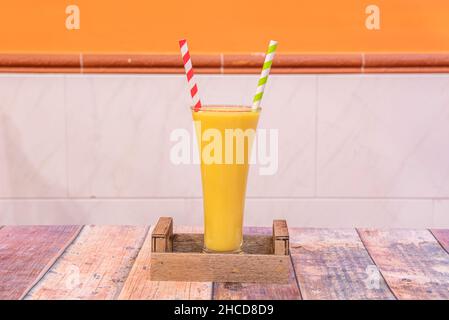 Zur Zubereitung der Mango-Lassi den Kefir (oder Joghurt) in ein amerikanisches Glas geben und einen Kardamom-Samen, den Kurkuma und die gehackte Mango dazugeben. Mit Witz bestreuen Stockfoto