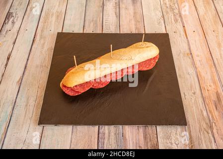 Spanisches Salami-Sandwich mit Baguette-Brot auf einem Pizzateller Stockfoto