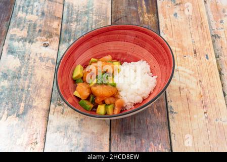 Lachs und Avocado-Tartare mit gekochtem weißen Reis auf einem Holztisch Stockfoto