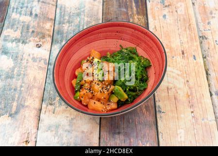 Roter Thunfisch und Avocado-Tartare mit Wakame-Algensalat mit Sesam und Mohn auf Holztisch Stockfoto