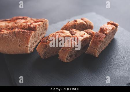 Hausgemachtes, frisch gebackenes, köstliches Brot gebackenes Baguette mit Getreidemehl auf schwarzem Hintergrund Stockfoto