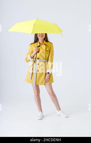Fröhliche junge Frau mit Regenschirm im Studio Stockfoto