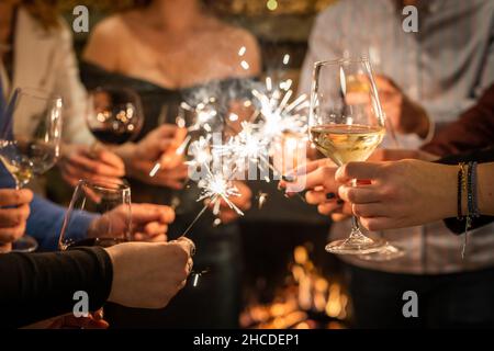 Nahaufnahme der Hände einer Gruppe von Menschen, die Gläser Wein halten und funkeln, während sie toasten und den Fokus im Innenbereich auf ein Glas Wein zum Geburtstag oder neu feiern Stockfoto