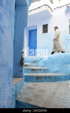 Ein Einheimischer, der durch die engen Straßen der Medina von Chefchaouen, Marokko, spazierengeht. Stockfoto