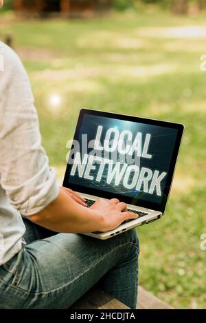 Schild mit Anzeige des lokalen Netzwerks. Business Showcase Intranet LAN Radio Waves DSL Boradband Switch Connection Frau tippt auf Laptop draußen sitzend Stockfoto