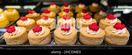 Kuchen im Schaufenster der Süßwaren oder des Cafés. Frisches Gebäck auf einem Süßwarenstand auf dem berühmten Granville Markt in Vancouver Stockfoto