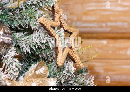 Schneebedeckter Weihnachtsbaum auf einem hölzernen Hintergrund mit Spielzeug, einem Stern. Winterpostkartenkonzept. Weicher Fokus. Stockfoto