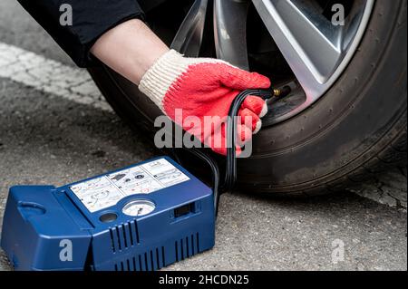 Mann, der Luft in den Reifen einfüllt. Autofahrer Prüft Den Luftdruck. Stockfoto