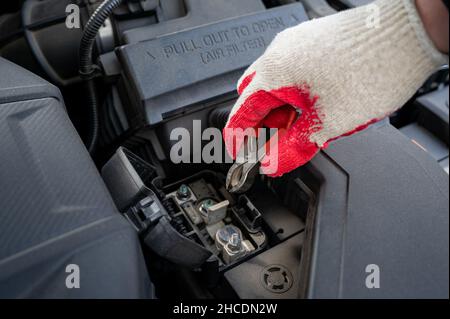 Die Hand des Fahrers prüft den Zustand der Fahrzeugbatterie. Stockfoto