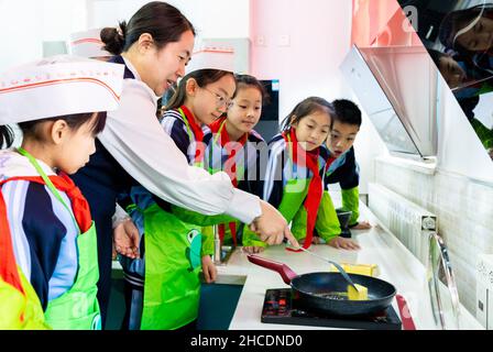 HOHHOT, CHINA - 28. DEZEMBER 2021 - Grundschüler lernen in Hohhot, der Autonomen Region Innere Mongolei Nordchinas, Nougatbonbons zu machen,
