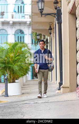 Junger Latino-Mann, der mit seinem Laptop die Straße entlang geht, Panama City, Mittelamerika Stockfoto