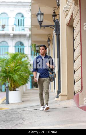 Junger Latino-Mann, der mit seinem Laptop die Straße entlang geht, Panama City, Mittelamerika Stockfoto
