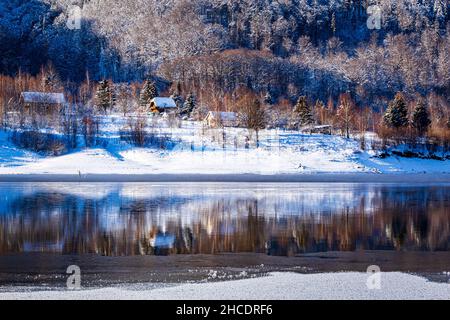 Kleine Waldhütten am Ufer des Poiana Marului Sees während eines perfekten Wintertages. Foto aufgenommen am 17th. Januar 2021 in Poiana Marului Reservation, Stockfoto