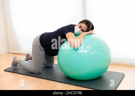 Eine Schwangerin macht Atemübungen und ruht sich auf einem Fitnessball aus Stockfoto