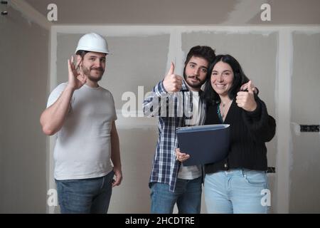 Das junge Paar und der Architekt feiern die Unterzeichnung des Vertrages zum Kauf eines Hauses. Stockfoto