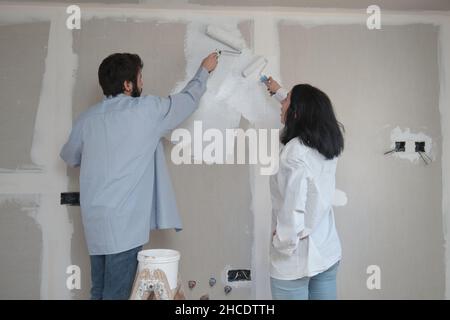 Junges Paar malt Wände in ihrem neuen Haus im Bau. Stockfoto