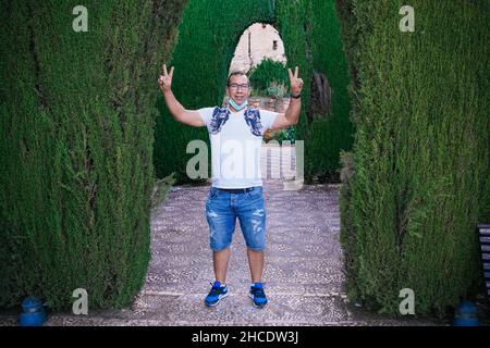 Porträt eines aufgeregten Mannes, der seine Arme umringt von Pflanzen hebt Stockfoto