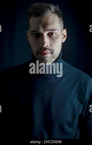 Porträt eines jungen Mannes im schwarzen Rollkragen mit einem intensiven und fesselnden Look Stockfoto