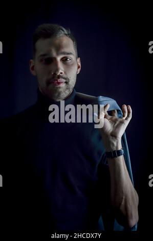 Porträt eines jungen Geschäftsmannes, der seine Jacke über die Schulter hält und aufmerksam vor ihn blickt Stockfoto
