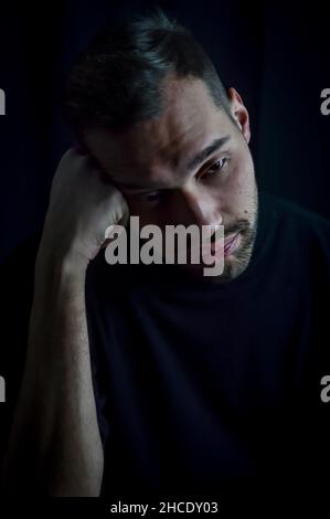 Porträt eines jungen Mannes, dessen Kopf auf der Faust liegt und sehr gelangweilt und deprimiert aussieht Stockfoto