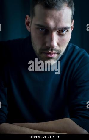 Porträt eines jungen Mannes im schwarzen Rollkragen mit einem intensiven und fesselnden Look Stockfoto
