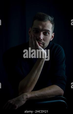 Nahaufnahme eines jungen Mannes, der sein Gesicht in der Hand hält und gelangweilt aussieht Stockfoto