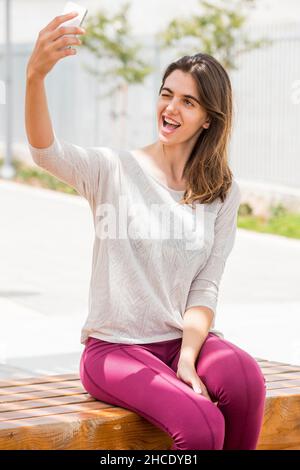 Junge Frau in legerer Sportkleidung nimmt ein Selfie draußen Stockfoto