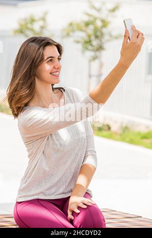 Junge Frau in legerer Sportkleidung nimmt ein Selfie draußen Stockfoto