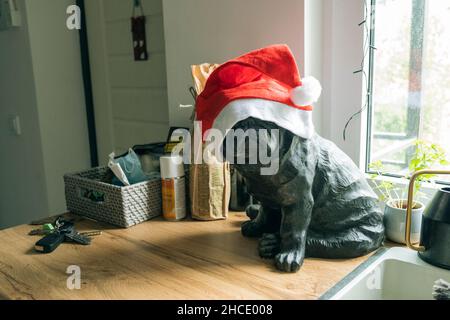 Hundefigur in rotem weihnachtsmütze in der Küche. Stockfoto