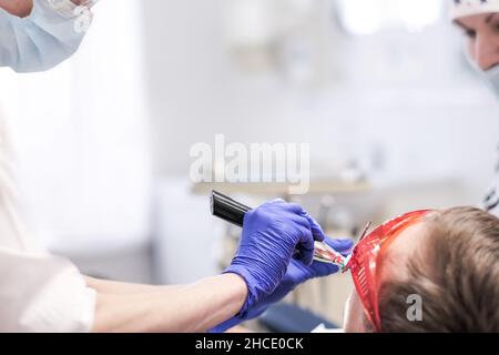 Der Zahnarzt empfängt den Patienten im Büro, er wird von einem Assistenten unterstützt. Speicherplatz kopieren Stockfoto