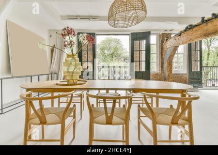 Essbereich mit Tisch und Stühlen in der Nähe von Balkon in geräumigen Wohnung bei Tageslicht eingerichtet Stockfoto