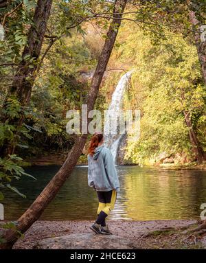 Rückansicht einer nicht erkennbaren Wanderin, die am Ufer des Flusses steht und den Wasserfall in Gorg de Santa Margarida bewundert Stockfoto