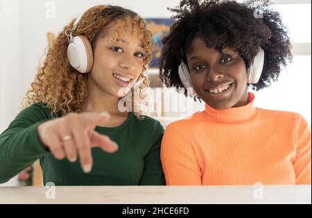 Positive afroamerikanische Freundinnen in lässiger Kleidung und mit afro-Frisur, die saluierende Gesten zeigen Stockfoto