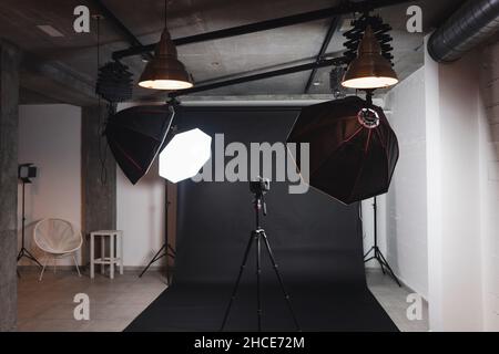 Interieur des modernen Fotostudios mit Octaboxen und professioneller Fotokamera auf Stativ vor schwarzem Hintergrund Stockfoto