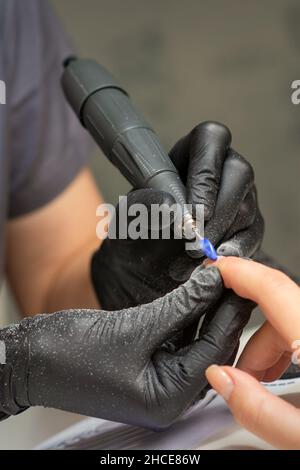 Manikurist entfernt Nagellack nutzt die elektrische Maschine der Nagelfeile während der Maniküre in einem Nagelstudio Stockfoto