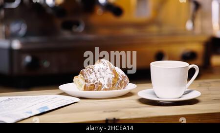tasse Kaffee in der Nähe von leckeren Croissants und Zeitung auf dem Tisch, Stockbild Stockfoto