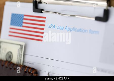 Dokumente für das amerikanische Visum und den amerikanischen Pass mit dem Geld, das auf dem Tisch liegt, werden aus der Nähe angezeigt Stockfoto