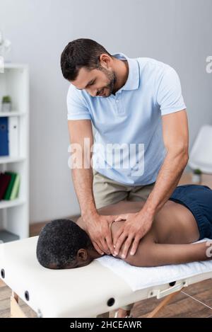 afroamerikanischer Mann bekommt Schultermassage im Reha-Zentrum Stockfoto
