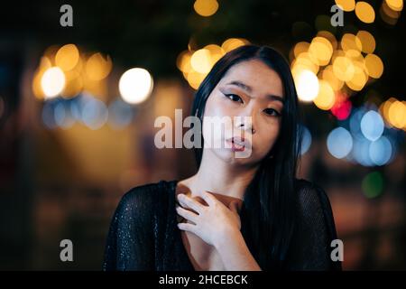 Porträt eines jungen asiatischen Mannes auf der Straße in der Nacht mit Lichtern im Hintergrund Stockfoto