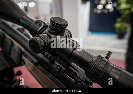 Schwarze Schießskop-Optik auf Gewehr montiert, die auf der Waffenmesse ausgestellt ist, Detailansicht der Einstellknöpfe Stockfoto