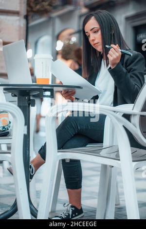 Geschäftsführerin eines wichtigen Unternehmens, die sich Notizen machte und Papierbögen mit Verträgen und Berichten über ihre Mitarbeiter für ihre Arbeit schrieb Stockfoto