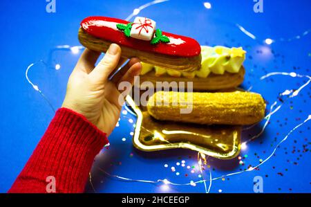 Das leckere eclair ist im Neujahrsstil dekoriert und hat eine Handansicht von oben. Weihnachtliche Süßspeisen. Stockfoto