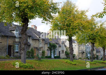 Anzeigen von Burford in den Cotswolds, zeigt die Cottages und die pollarded Linden am oberen Ende der High Street, Oxfordshire, England Stockfoto