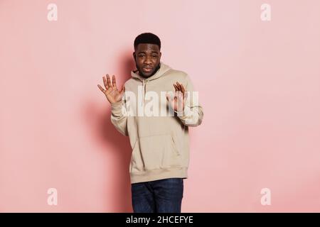 Studioaufnahme eines jungen verängstigten afrikanischen Mannes, der allein auf einem rosa Studiohintergrund mit Werberaum für Werbung steht. Stockfoto