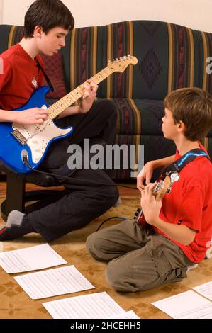 13-jähriger Junge zu Hause, der die E-Gitarre spielt und mit seinem 12-jährigen Bruder spielt Stockfoto